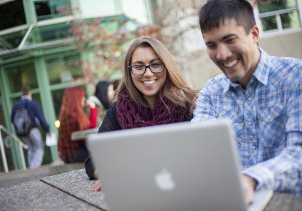 2 students smiling and looking at laptop