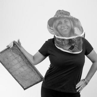 A smiling woman in a beekeeeper hat. 